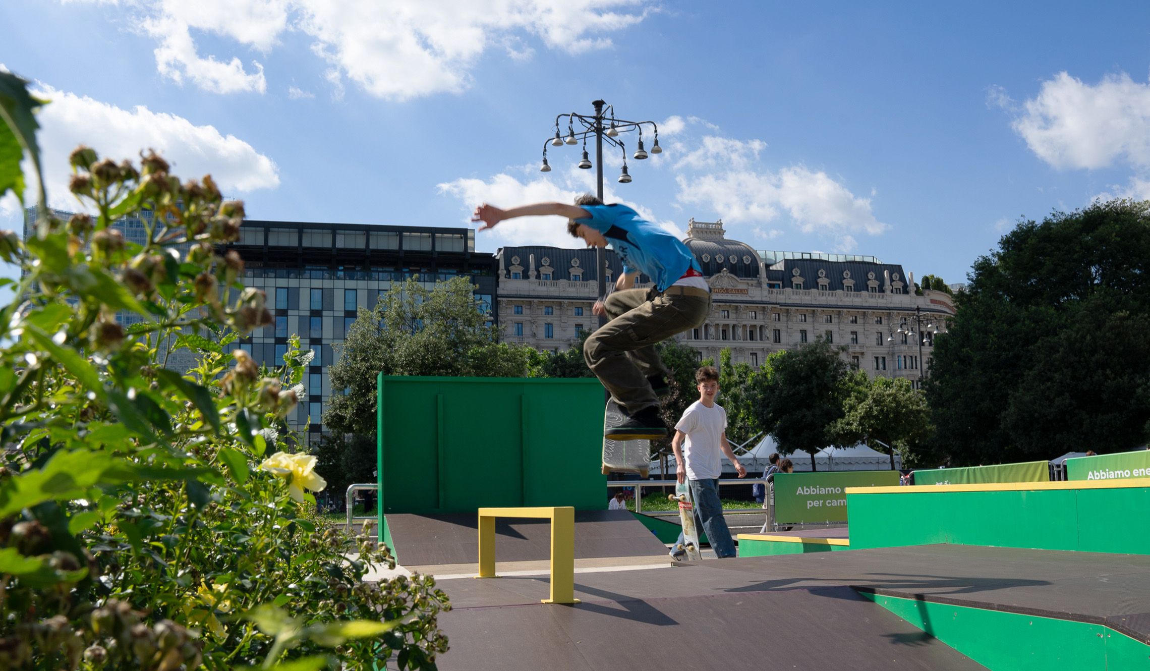 Lo skater park brandizzato Plenitude con uno ragazzo sullo skate e l’altro che lo guarda con lo skate in mano. Sullo sfondo, piazza Duca d’Aosta. 