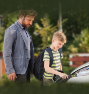 Un adulto e un bambino mentre ricaricano un’auto elettrica