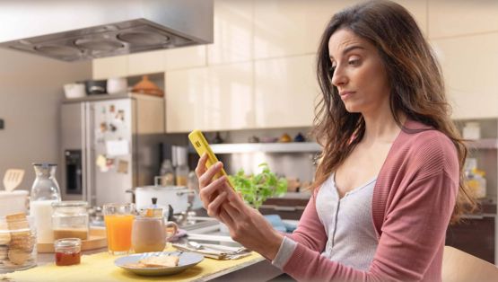 Una donna in cucina che guarda lo schermo di uno smartphone
