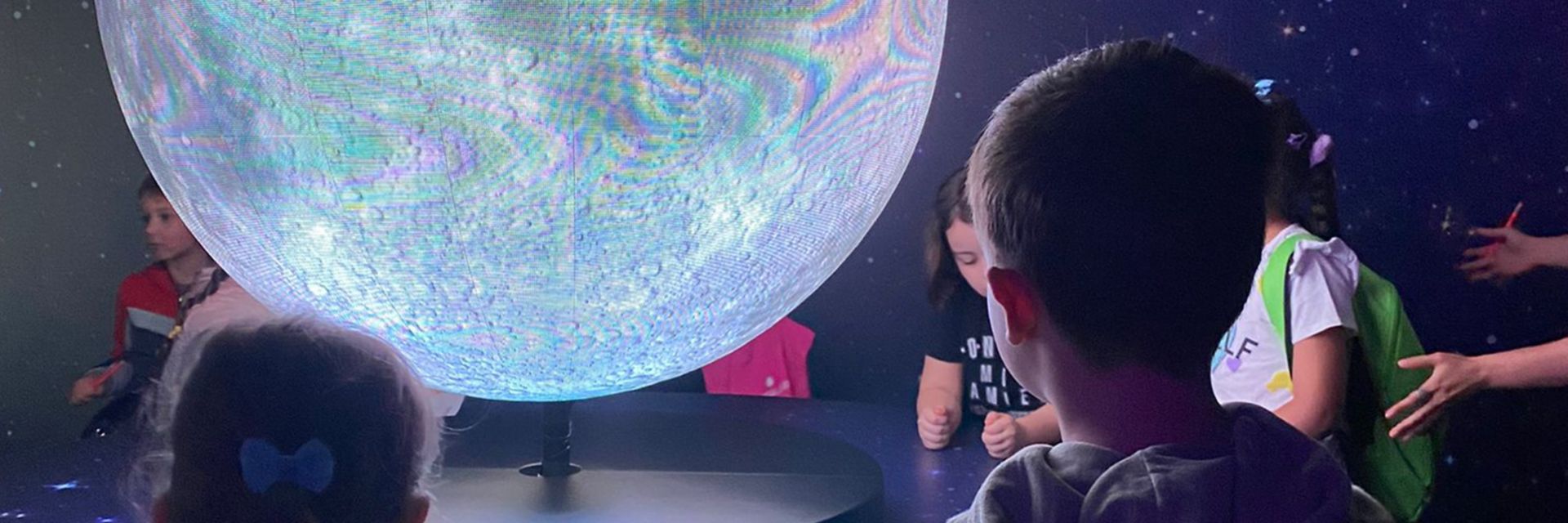 Bambini osservano un globo luminoso, durante un incontro educativo.