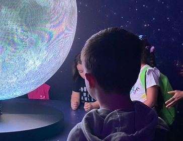 Children look at a glowing globe during an educational event.