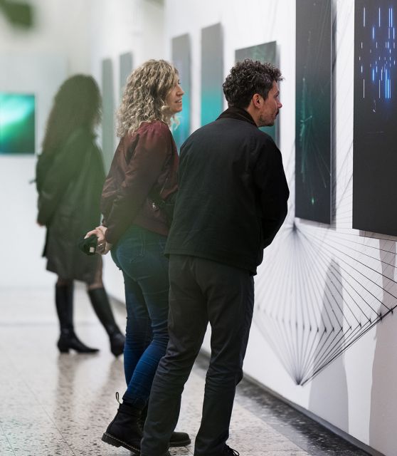 tre ragazzi che guardano i quadri della mostra