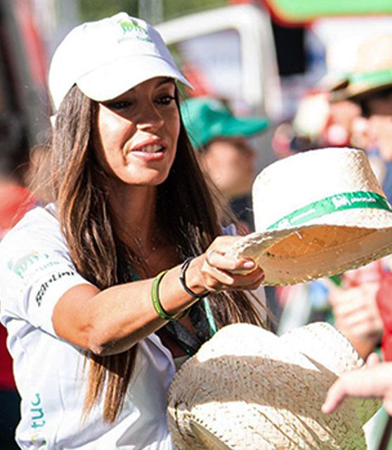 Une fille qui distribue des casquettes avec le logo de Plenitude