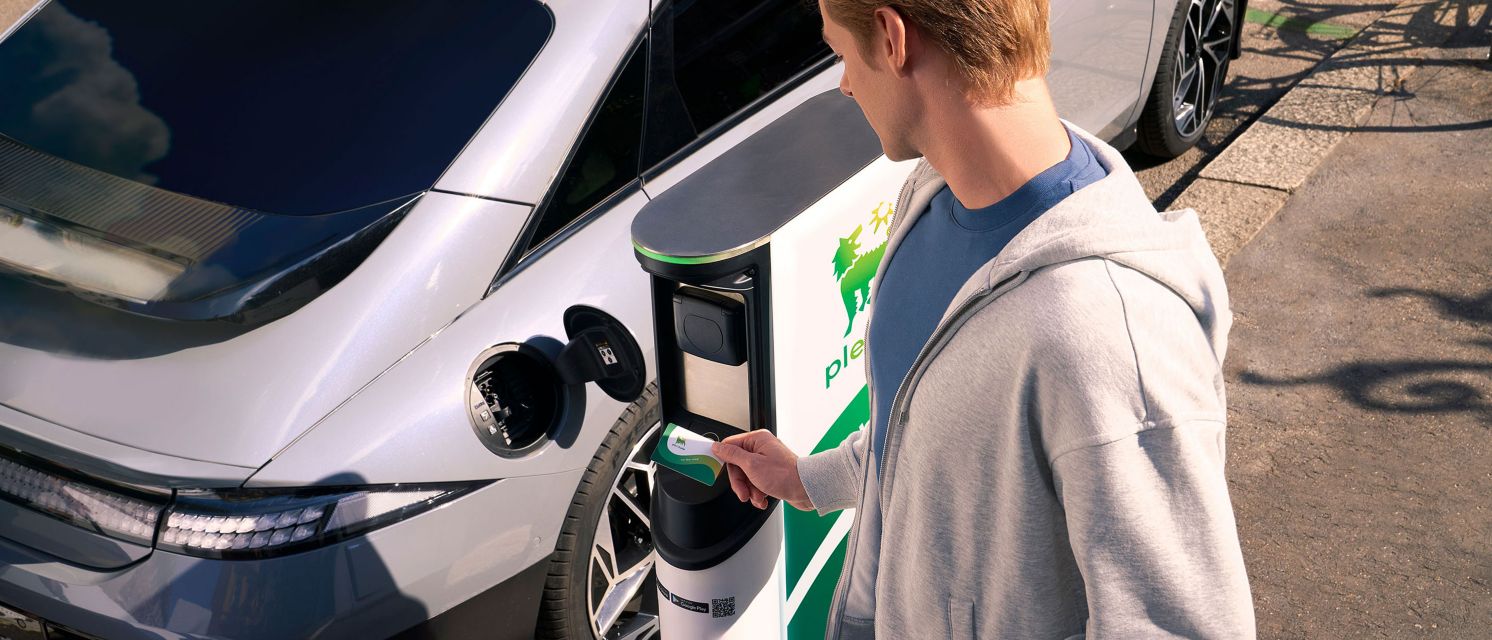 Conductor de coche eléctrico activando la recarga de su VE con la tarjeta RFID de Plenitude On the Road.