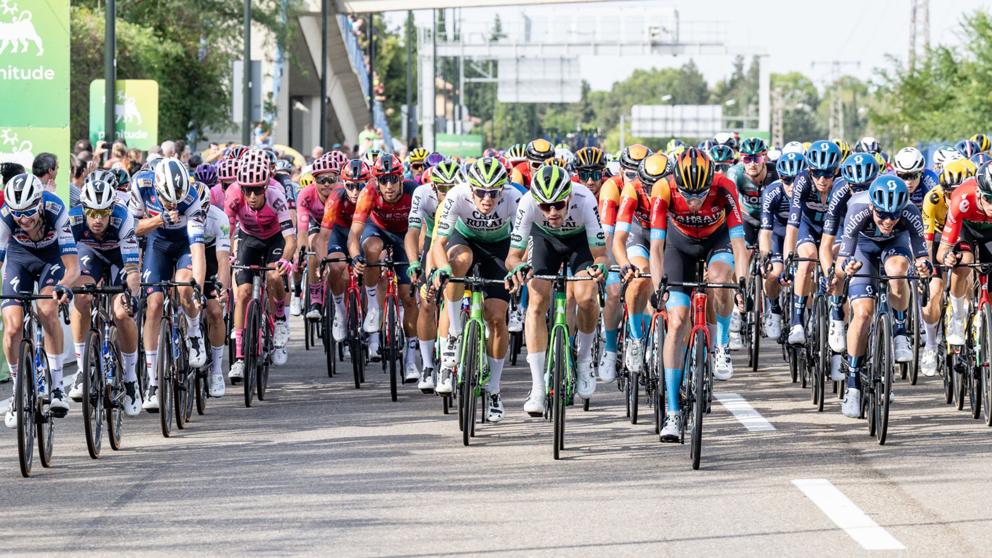 Pelotão ciclista da Volta com cartazes de patrocínio Plenitude