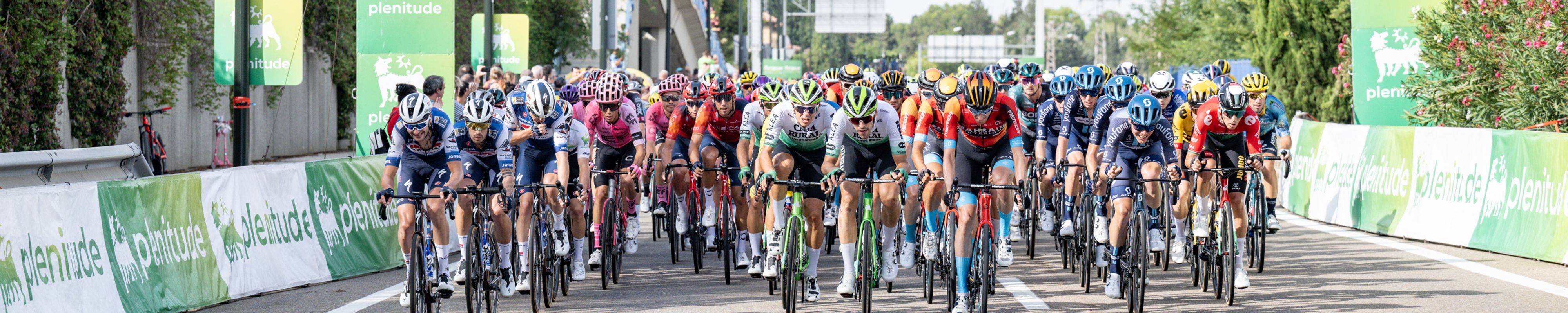 Pelotão ciclista da Volta com cartazes de patrocínio Plenitude