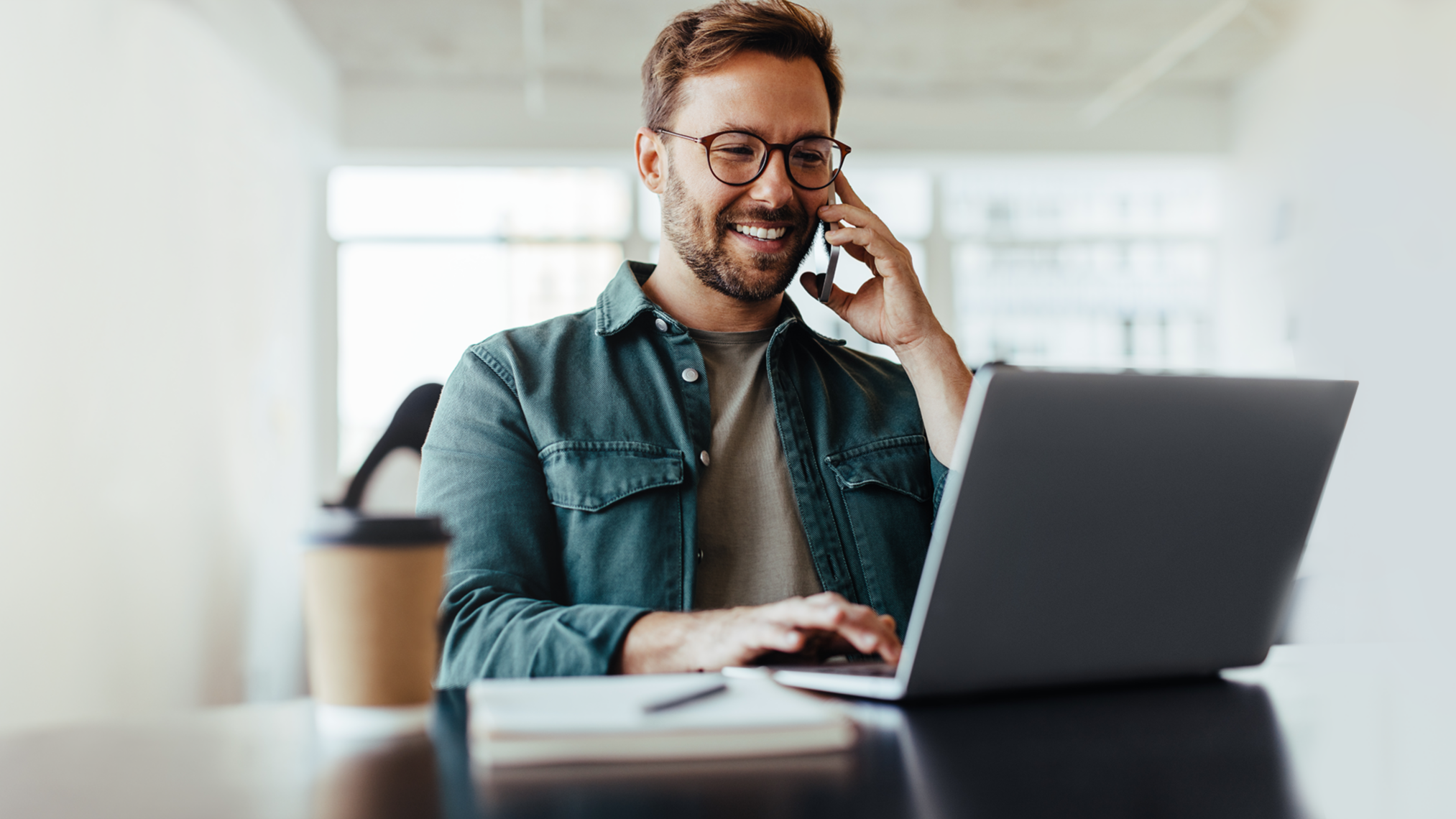 Chico joven con móvil y portátil