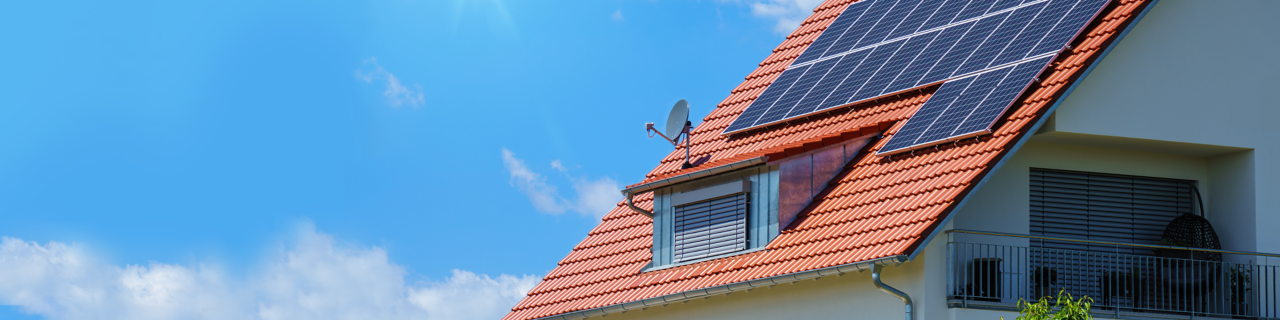 Imagen de una casa con placas solares instaladas en un día soleado