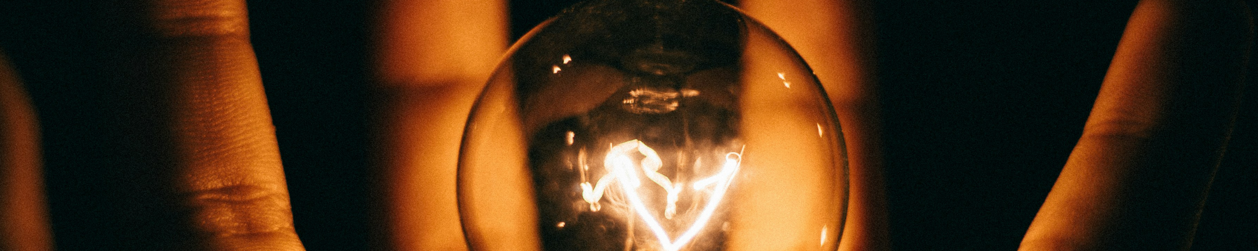 Bombilla encendida con mano de fondo