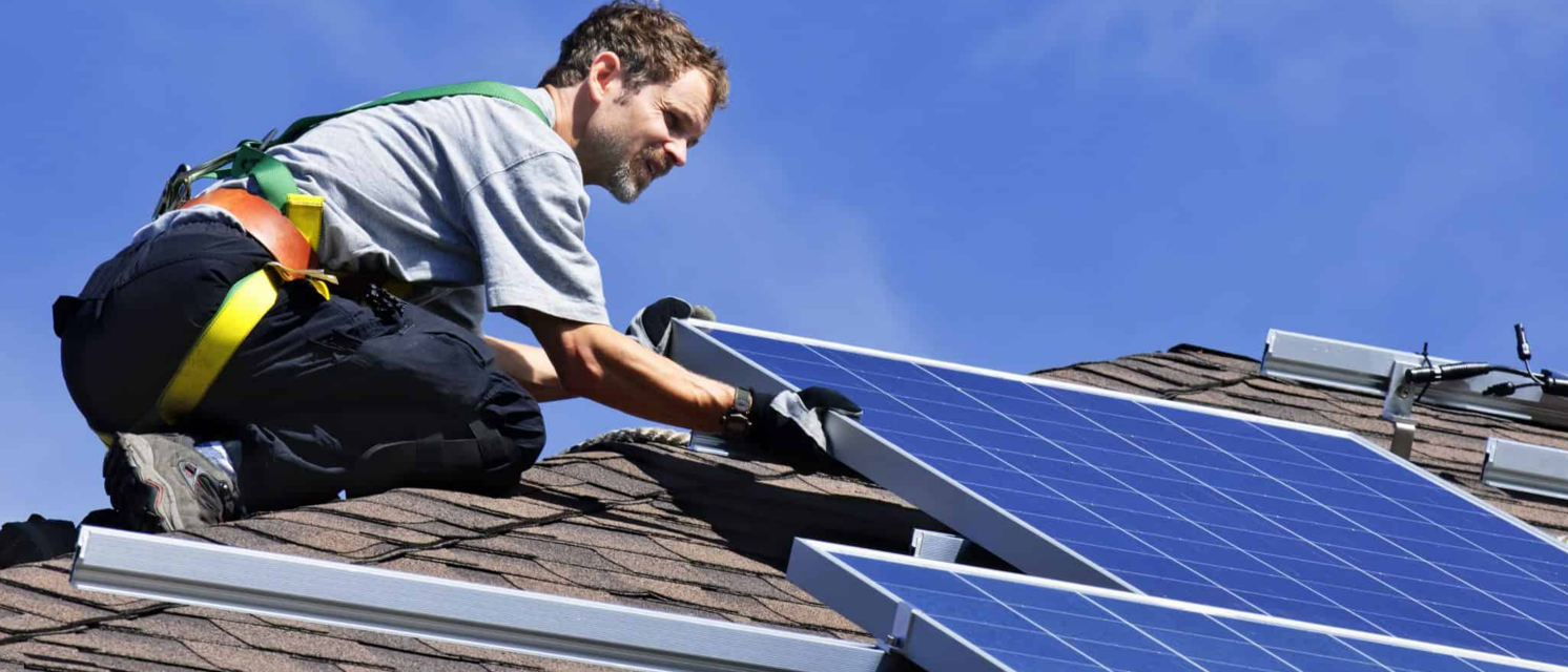 Instalador manejando placas solares en el tejado