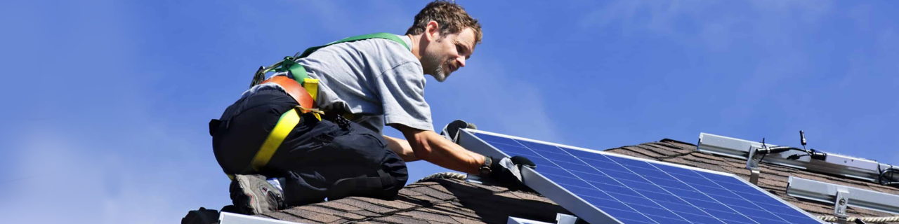 Instalador manejando placas solares en el tejado