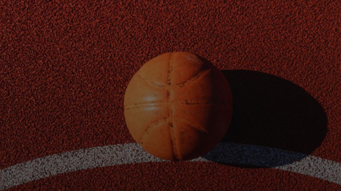 A top-down shot of an orange basketball resting on the ground on a red basketball court.
