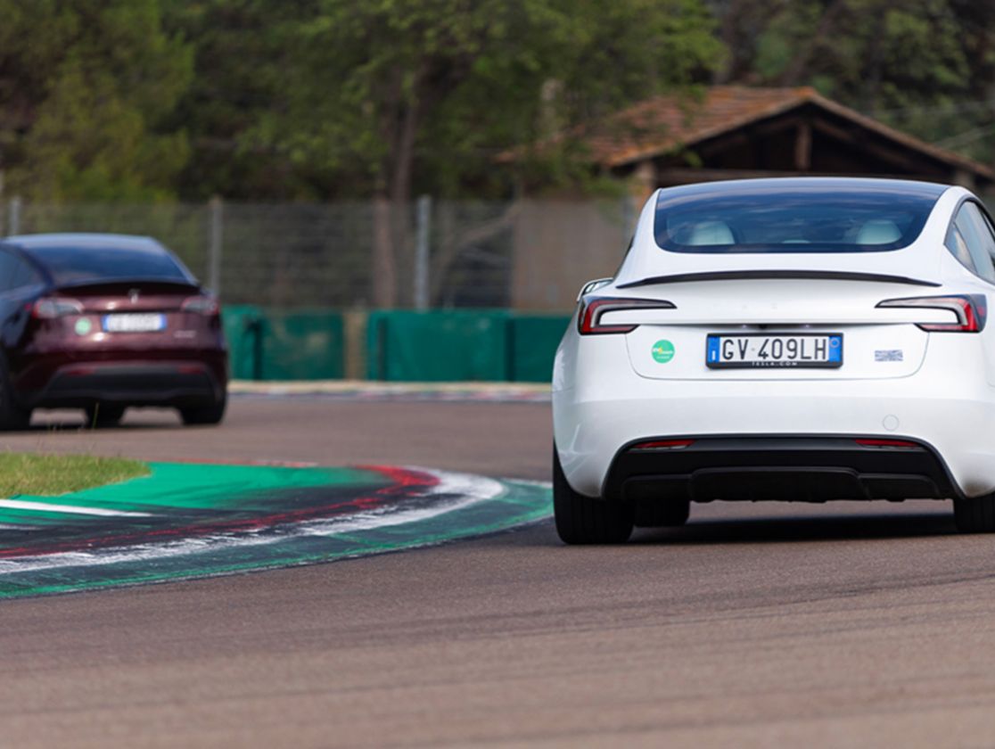 Due auto elettriche corrono in pista, la prima è bordeaux, la seconda bianca, entrambe si vedono da dietro e hanno il logo di Plenitude accanto alla targa.