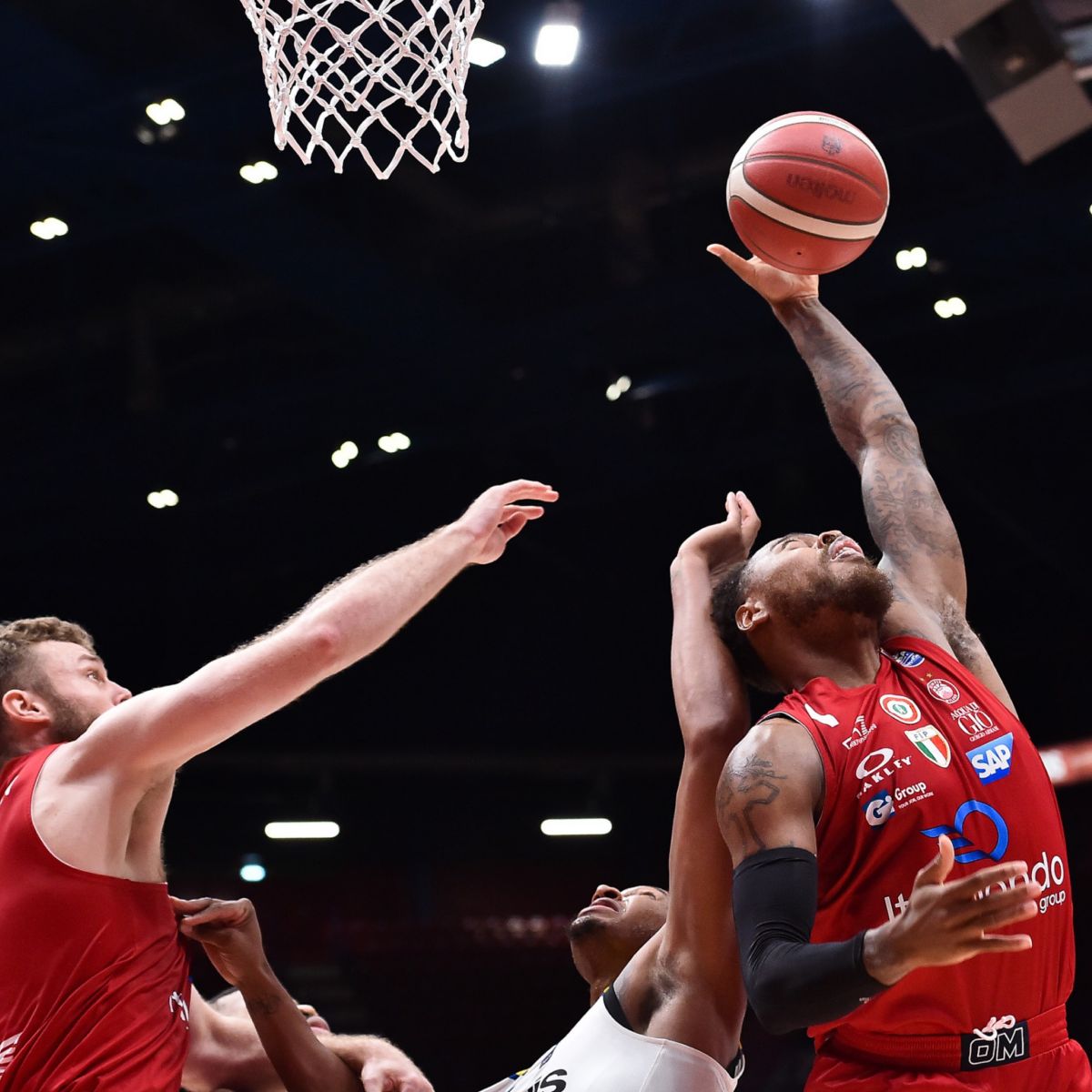 Some basketball players dressed in a red t-shirt, during an action near the hoop.