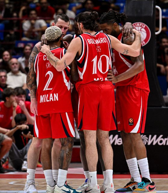 Due giocatori di basket con la maglia rossa con il logo Plenitude sono in primo piano di spalle, di fronte ad un terzo giocatore vestito uguale che li guarda stringendo un pugno in segno di vittoria. 