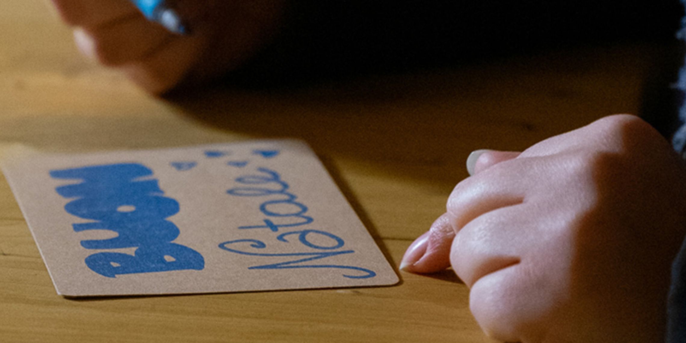 Le mani di un bambino scrivono Buon Natale su un cartoncino.