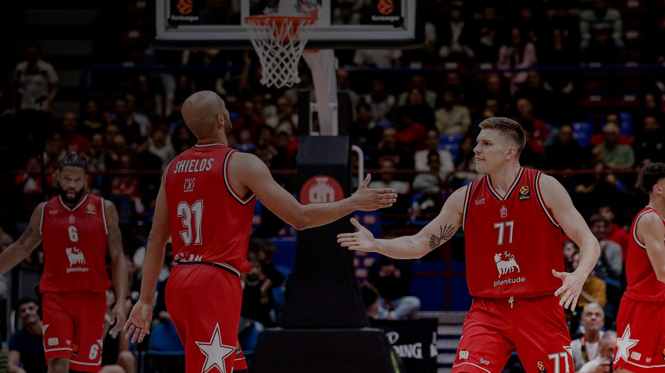 Players dressed in a red t-shirt, trying to catch the basketball with one arm.
