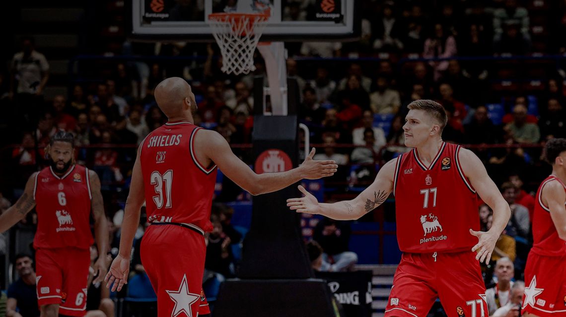 Players dressed in a red t-shirt, trying to catch the basketball with one arm.