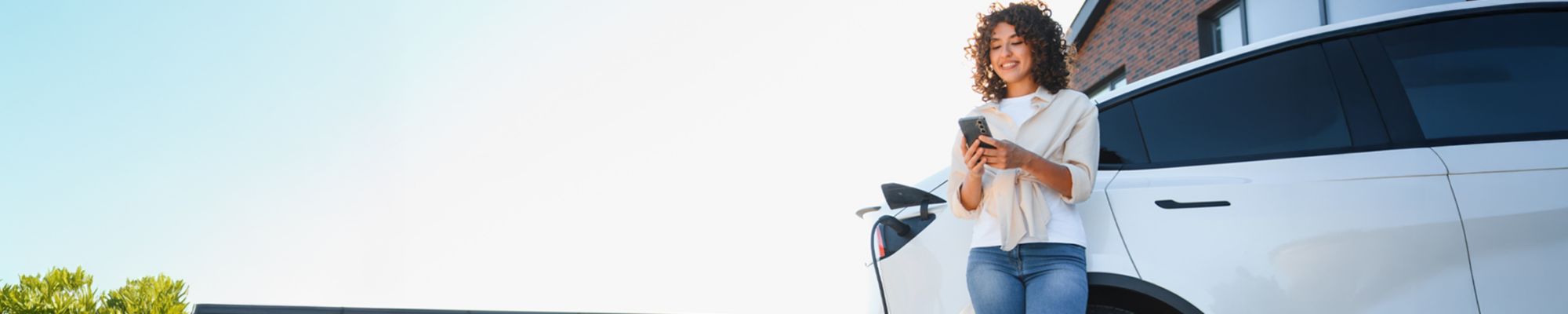 Immagine di una ragazza e di un'auto elettrica alla colonnina di ricarica