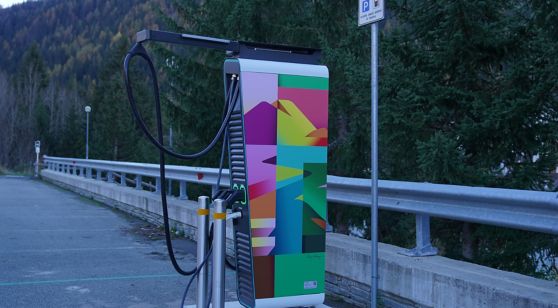 Su una strada c'è una colonnina per la ricarica di veicoli elettrici decorata con una delle opere del progetto "Art in motion" di Plenitude.