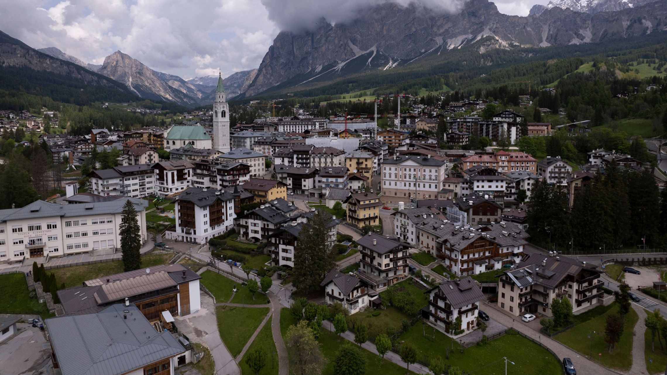 Una vista aerea della splendida cittadina alpina di Cortina d'Ampezzo, circondata dalle Dolomiti e da un cielo nuvoloso, in Italia.
