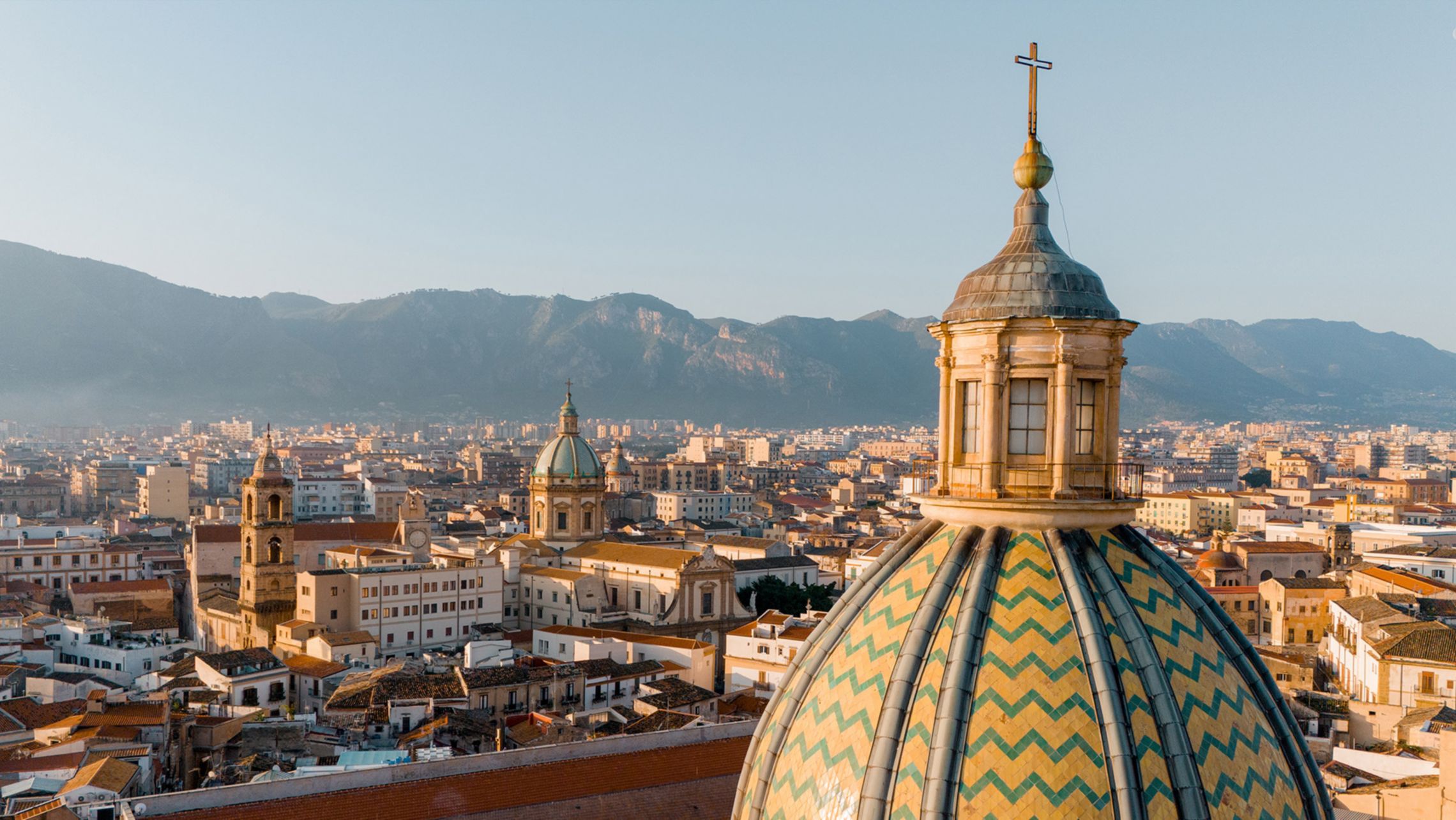 Close-up aerial view of Palermos iconic maiolica-tiled dome glowing in sunrise light