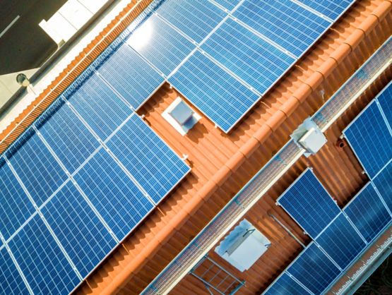 Aerial view of solar photo voltaic panels system on apartment building roof. Renewable ecological green energy production concept.; Shutterstock ID 1403947616; purchase_order: -; job: -; client: -; other: -