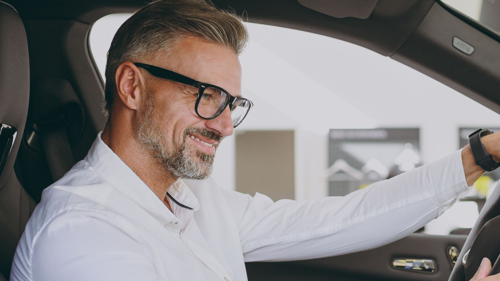 Adult man customer male buyer client wears shirt sit drive electric car hold steering wheel choose auto want to buy new automobile in showroom vehicle salon dealership store motor show. Sales concept; Shutterstock ID 2461248783; purchase_order: -; job: -; client: -; other: -