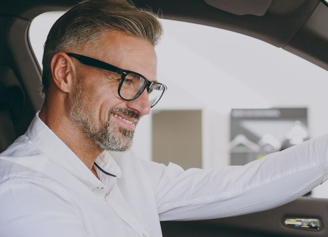 Adult man customer male buyer client wears shirt sit drive electric car hold steering wheel choose auto want to buy new automobile in showroom vehicle salon dealership store motor show. Sales concept; Shutterstock ID 2461248783; purchase_order: -; job: -; client: -; other: -