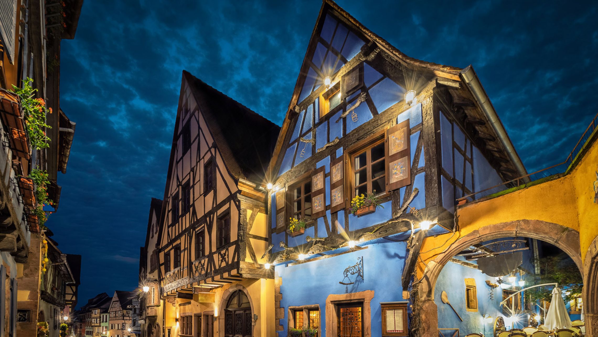 Colorful traditional half-timbered french houses on central street of Riquewihr village in the evening, Alsace, France