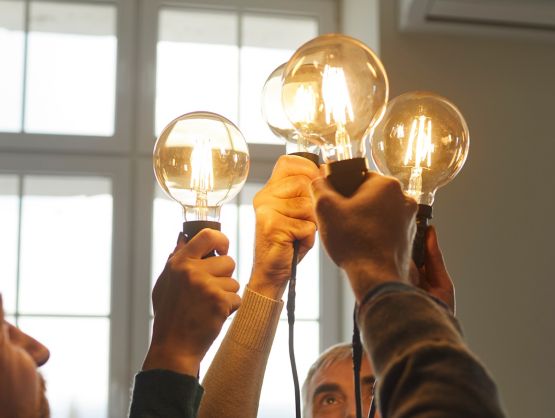Team of creative minds. Group of smiling intelligent young and senior people holding and raising up bright, shining, glowing Edison light bulbs as symbol of developing collective ideas and innovations; Shutterstock ID 2079249214; purchase_order: -; job: -; client: -; other: -