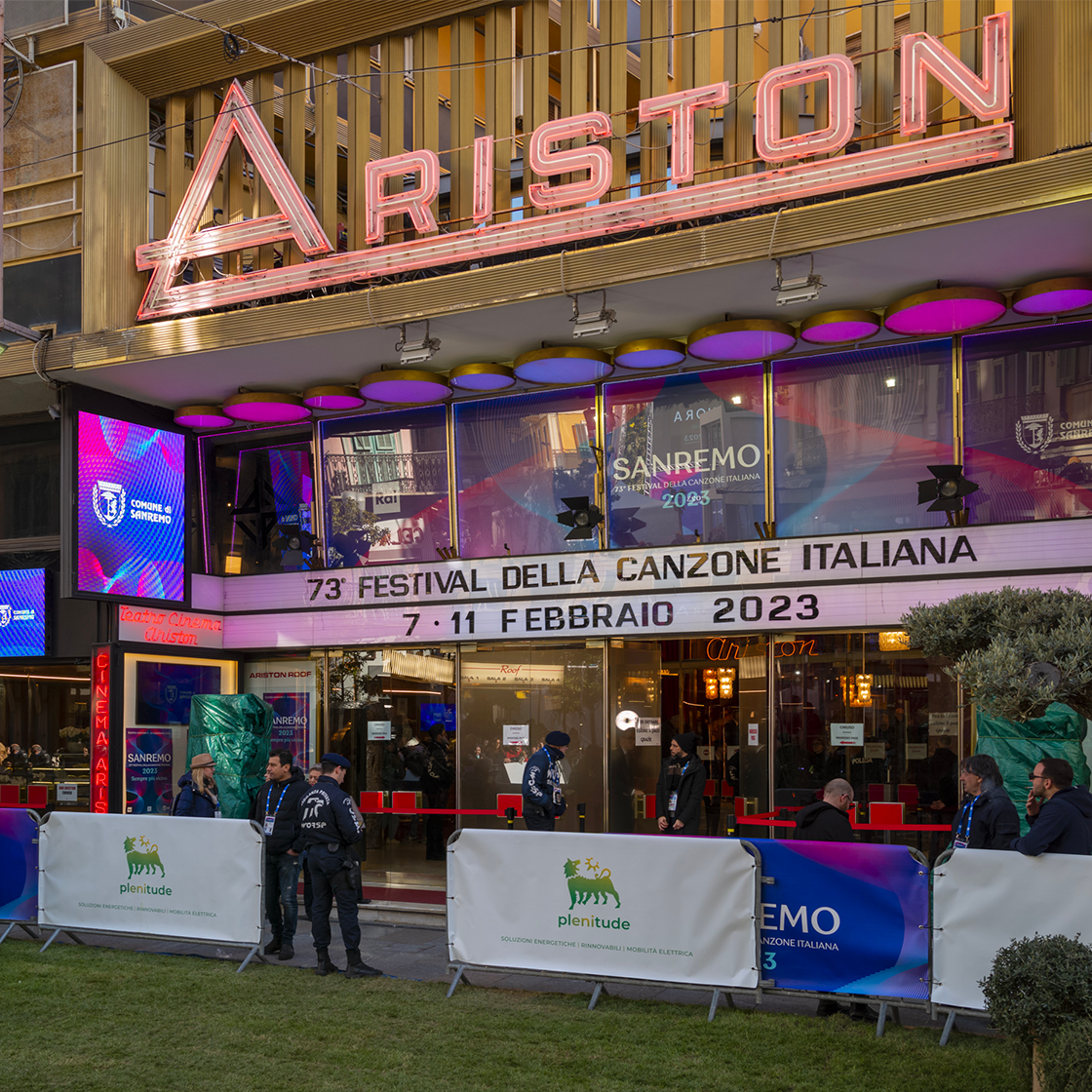 Picture of the facade of the Ariston theatre. There is a neon sign saying “Ariston” and below it another sign saying in Italian: “73th festival of Italian songs, 7-13 February 2023”. 