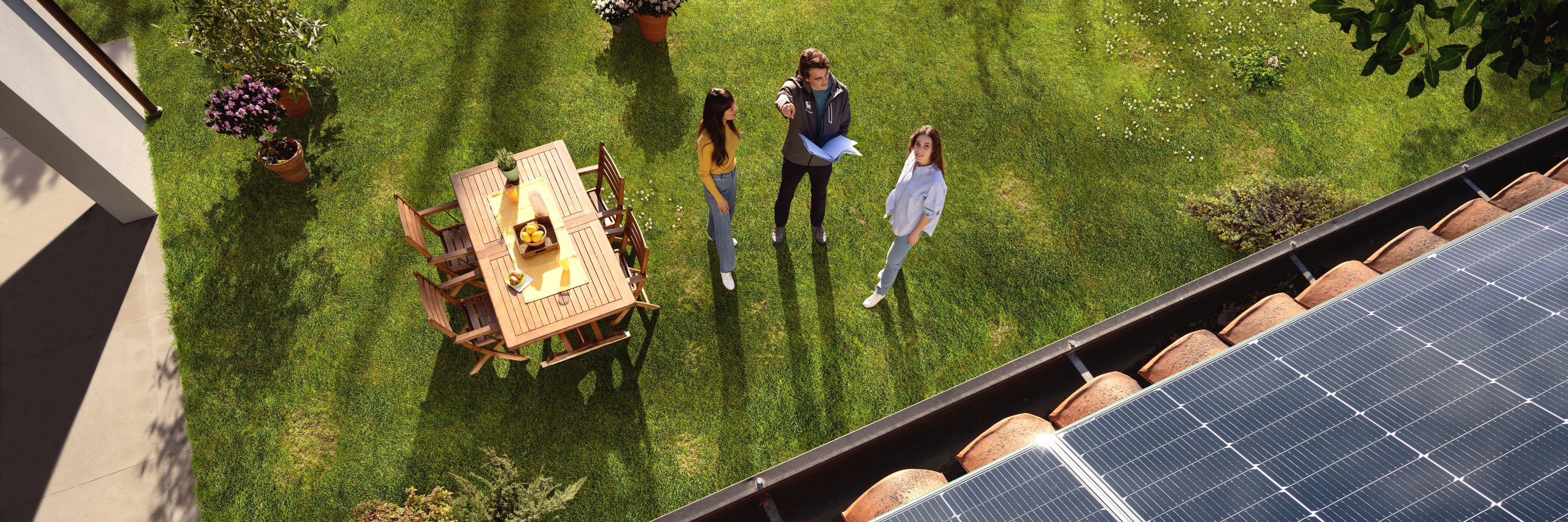 Tre persone che indicano dei pannelli solari sul tetto